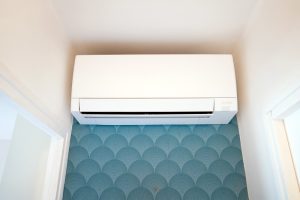 Climatiseur mural blanc sur le mur du couloir d'une maison, habillé en papier peint bleu